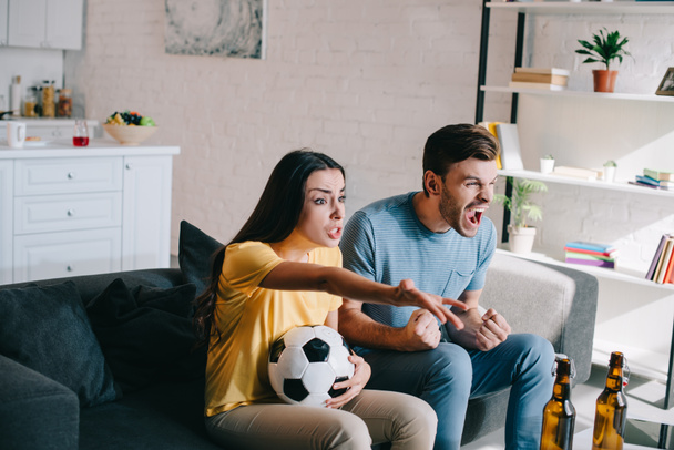 expressive shouting young couple watching football game at home - Фото, изображение