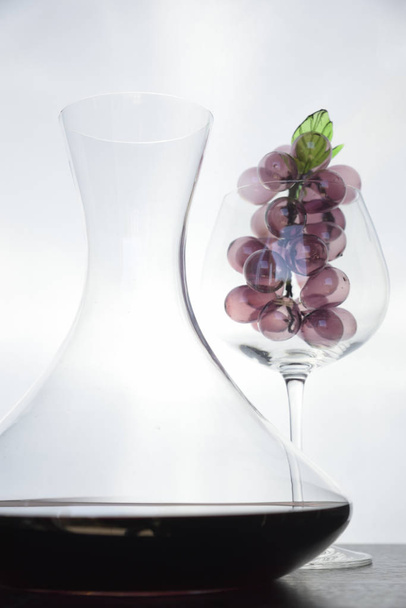 Ιταλικό κόκκινο κρασί στο εσωτερικό του decanter και κύλικα με διακοσμήσεις. - Φωτογραφία, εικόνα