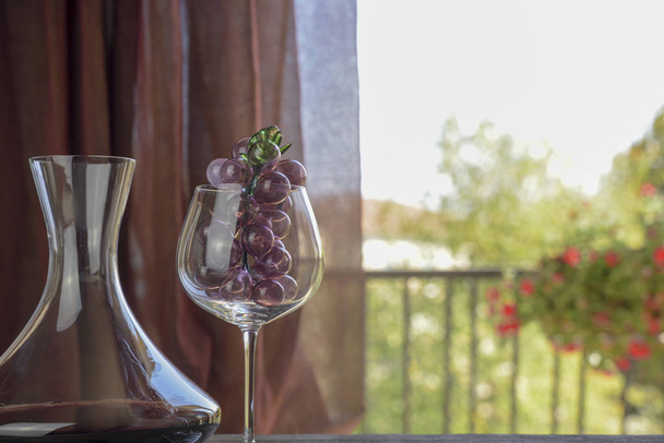 italienischer Rotwein in der Karaffe und im Becher mit Dekorationen. Natürlicher Hintergrund - Foto, Bild