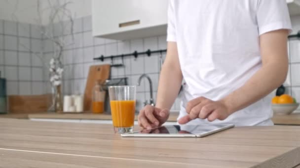 close-up of hands and fingers of a business man tapping the screen of a tablet computer. close up of man with tablet pc computer and cup of orange juice at home - Video