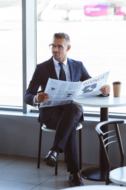 adult handsome businessman in glasses reading newspaper in cafe at airport - Photo, Image