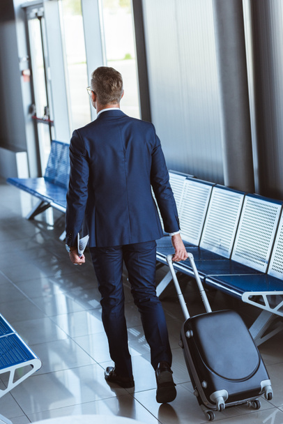 back view of businessman with travel bag walking at airport - Fotó, kép