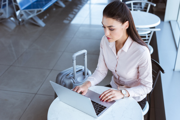 jovem empresária com bagagem usando laptop no aeroporto
 - Foto, Imagem