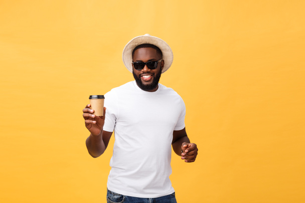 Κομψό νεαρός αφρικανική αμερικανική άνθρωπος που κρατώντας το Κύπελλο του take away καφέ που απομονώνονται σε κίτρινο φόντο. - Φωτογραφία, εικόνα