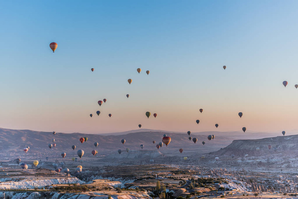 View of hundred of hot air balloons flying all over Cappadocia region from the highest point in Uchisar during the sunrise in the morning, Turkey - Foto, afbeelding