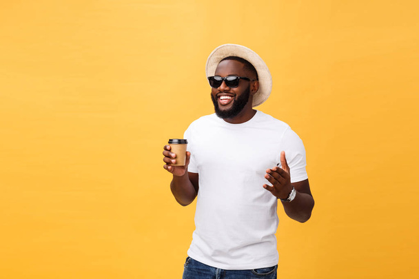 Stylish young african american man holding cup of take away coffee isolated over yellow background. - Фото, зображення