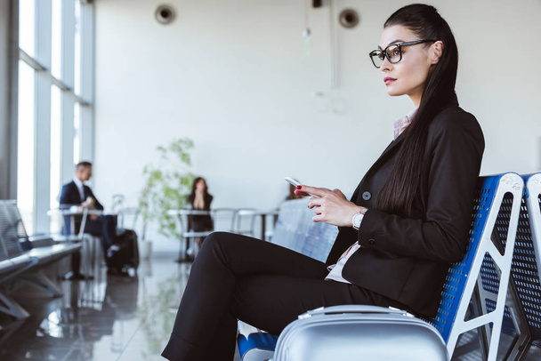 young businesswoman in glasses using smartphone at departure lounge in airport - Foto, immagini