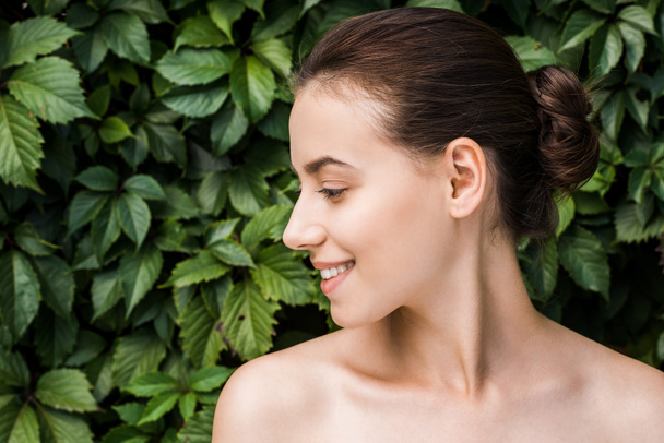 smiling young woman with green leaves at background  - Photo, Image
