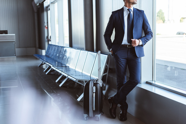 επιχειρηματίας στέκεται στο σαλόνι αναχώρησης και κοιτάζοντας παράθυρο στο αεροδρόμιο - Φωτογραφία, εικόνα