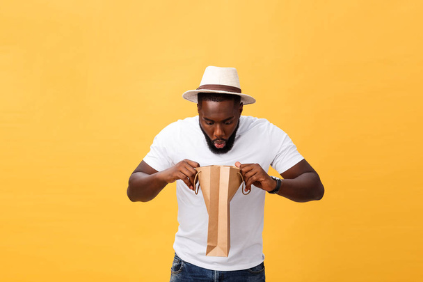African American man with colorful paper bags isolated on yellow background - Foto, Bild