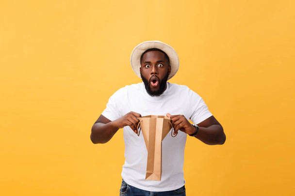 African American man with colorful paper bags isolated on yellow background - Fotó, kép