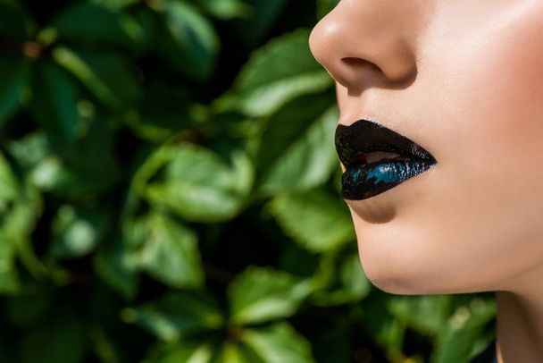 close up of female black shiny lips on green background  - Foto, Imagen
