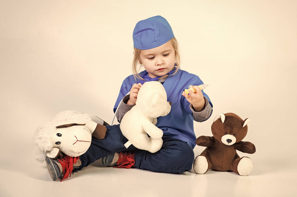 small boy in doctor uniform playing vet with toy animal - Zdjęcie, obraz