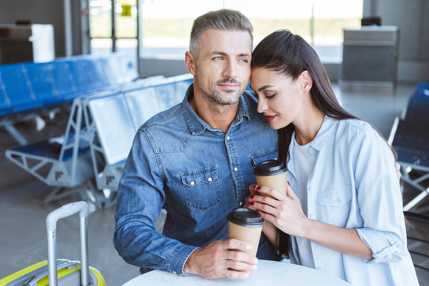 pareja adulta con café para ir abrazando en el aeropuerto
 - Foto, imagen