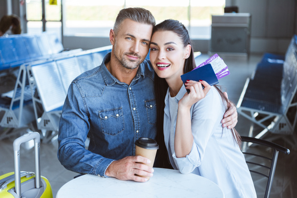 Couple sitting in the airport with coffee, passport and ticket - Foto, imagen