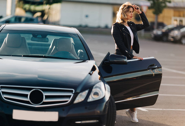 Photo of nice blonde at open door of black car - Valokuva, kuva