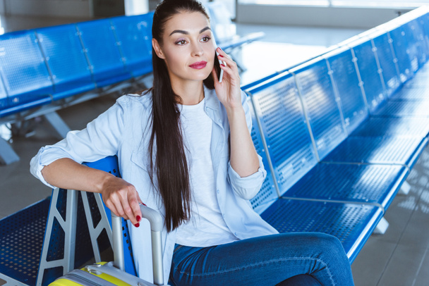 Όμορφο κορίτσι μιλάει στο smartphone και η αναμονή για το αεροπλάνο στο αεροδρόμιο - Φωτογραφία, εικόνα