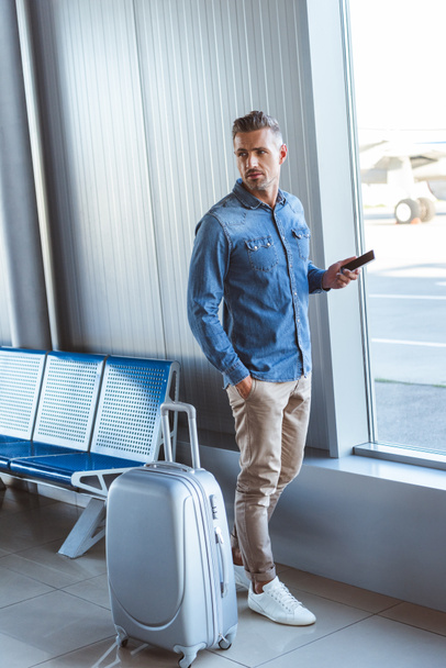 Homme en chemise bleue gardant le téléphone dans la main et regardant quelque chose à l'aéroport
 - Photo, image