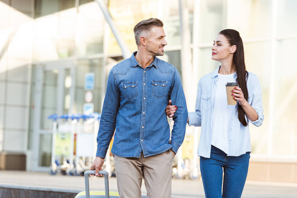 Boldog pár turista keresztező gyalogos, gazdaság kezét, és húzza a poggyász  - Fotó, kép