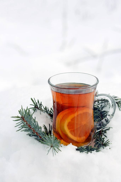 Una tazza di tè caldo con fette di arancia sulla neve. Rami di abete. L'umore di Natale
 - Foto, immagini
