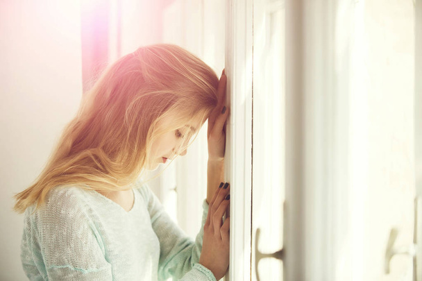 Pretty girl leaned against window frame - Фото, зображення