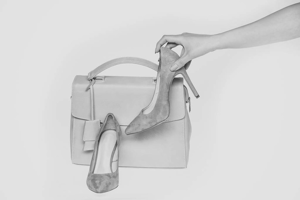 Χέρι κρατήστε παπούτσια τσάντα που απομονώνονται σε λευκό φόντο. Τσάντα και θηλυκό Στιλέτα του κοραλί χρώμα, δερμάτινο υλικό. Μόδα, στυλ, αξεσουάρ έννοια - Φωτογραφία, εικόνα