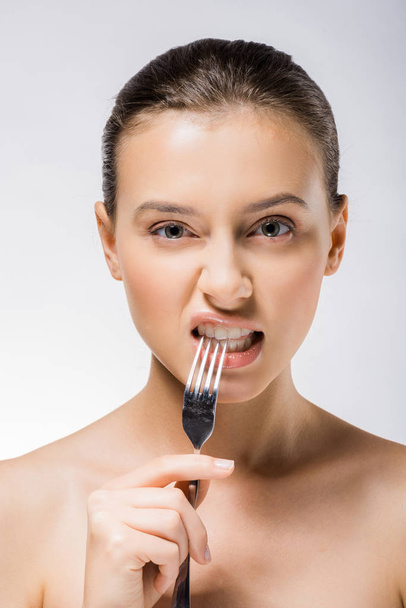 young beautiful woman holding silver fork near teeth  - Valokuva, kuva
