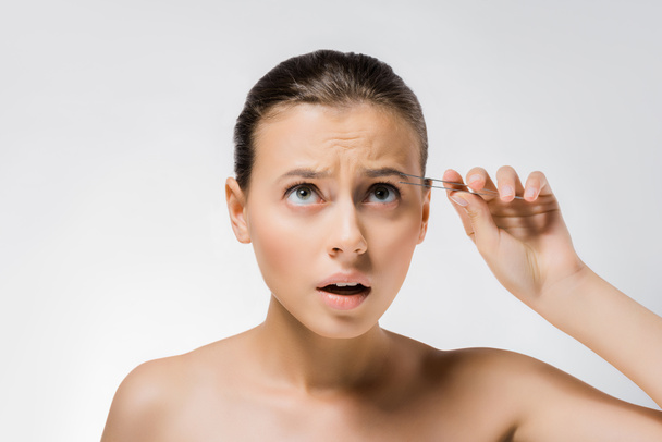 young confused woman holding metal tweezers near face  - Fotoğraf, Görsel