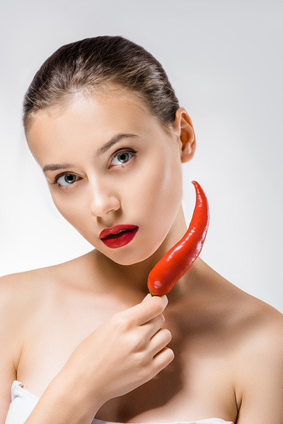 young beautiful woman with red lips holding chili pepper near face - Фото, зображення