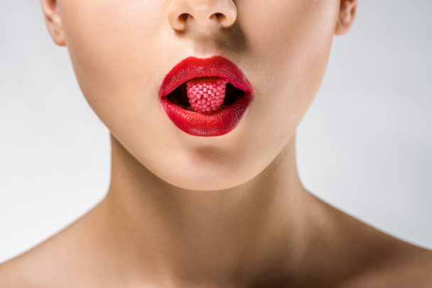 close up of young woman with red lips holding red candy in mouth - Fotoğraf, Görsel