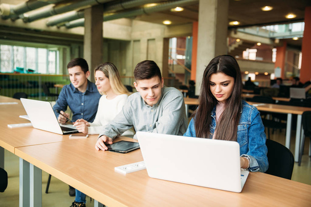 Gruppe von College-Studenten, die in der Schulbibliothek lernen, ein Mädchen und ein Junge benutzen einen Laptop und verbinden sich mit dem Internet - Foto, Bild