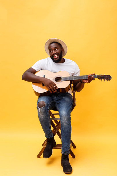 Full-length photo of excited artistic man playing his guitar. Isolated on yellow background. - Photo, image