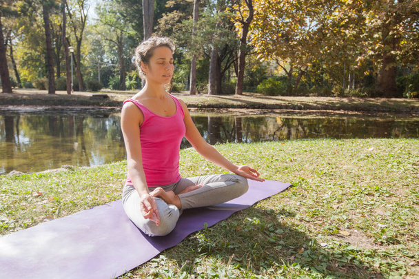 Mujer meditando y practicando yoga en el parque en hermoso día soleado del otoño
 - Foto, Imagen