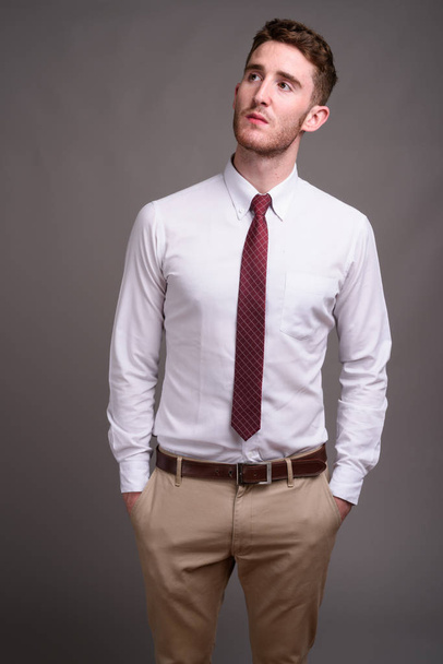 Portrait of young handsome businessman against gray background - Fotografie, Obrázek