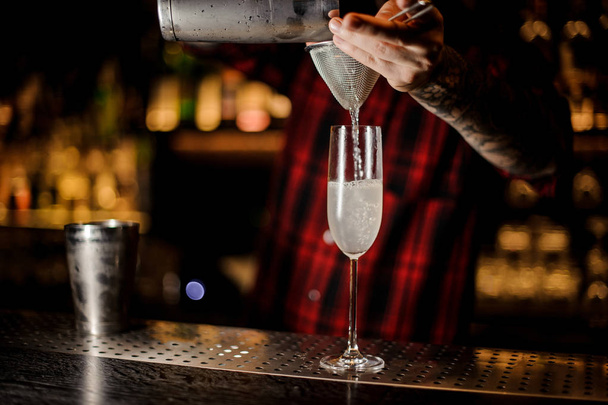 Barman making a fresh French 75 cocktail using a shaker and strainer on the bar counter - Fotografie, Obrázek