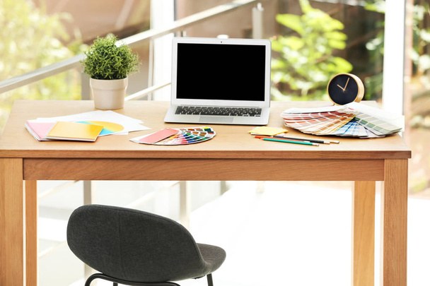Lugar de trabajo del diseñador con ordenador portátil y muestras de paleta de colores de pintura en la mesa
 - Foto, imagen