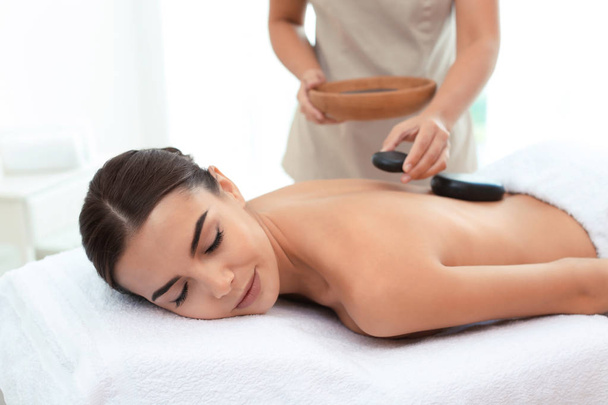 Mulher bonita recebendo massagem de pedra quente no salão de spa
 - Foto, Imagem