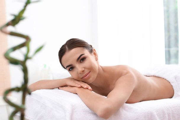 Beautiful young woman lying on massage table in spa salon - Foto, imagen