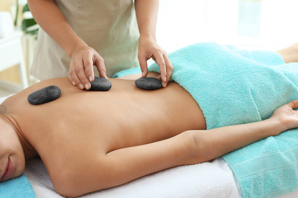 Beautiful young woman getting hot stone massage in spa salon - Фото, зображення