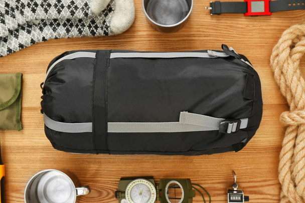 Composition à plat avec sac de couchage et équipement de camping sur fond en bois
 - Photo, image