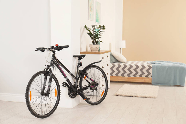 Bicycle near light wall in stylish room interior - Valokuva, kuva