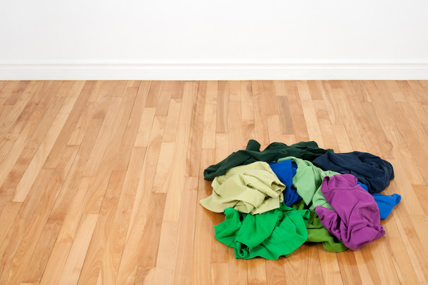 σωρό από πολύχρωμα ρούχα στο ξύλινο πάτωμα - Φωτογραφία, εικόνα
