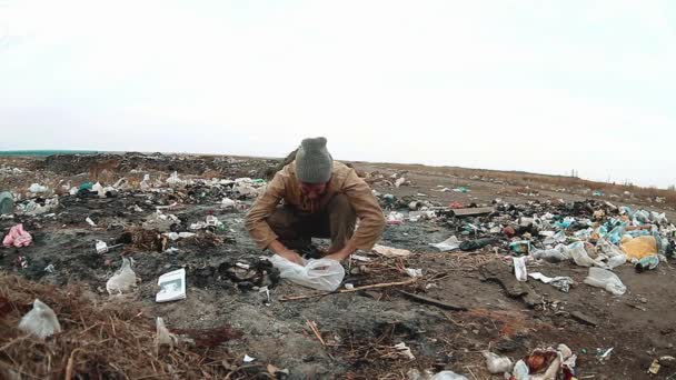 man dakloze dump in een dakloze van een stortplaats op zoek is naar voedsel onder de vuilnis. sociale concept levensstijl probleem armoede honger man. probleem van de armoede en sociale ongelijkheid concept - Video