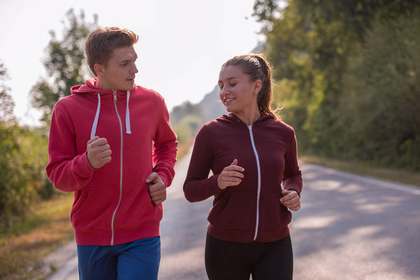 young couple enjoying in a healthy lifestyle while jogging along a country road, exercise and fitness concept - Фото, зображення