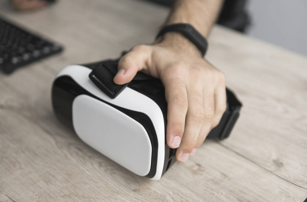 VR virtual reality glasses on a table with a man hand. - Photo, Image