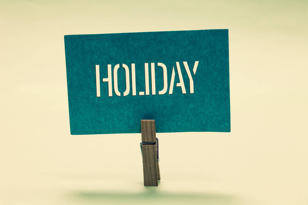 Handwriting text Holiday. Concept meaning Extended period of leisure recreation Vacation Celebration days Clothespin holding turquoise paper important communicate message ideas. - Foto, imagen