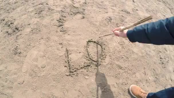 Mann schreibt Liebesworte in den Sand. - Filmmaterial, Video