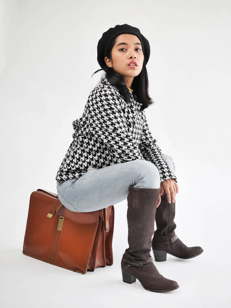 Portrait of Asian woman wearing winter jacket and sitting on vintage brown bag, winter lifestyle fashion. - Fotoğraf, Görsel