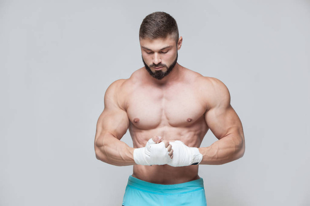 Muscular Fighter kickbox With white Bandages against the grey background - Foto, Imagem
