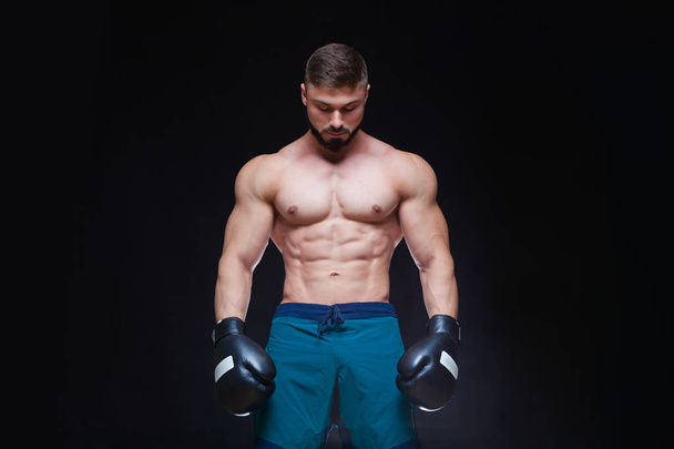 Strong muscular boxer in black boxing gloves. Isolated on black background. - Fotoğraf, Görsel